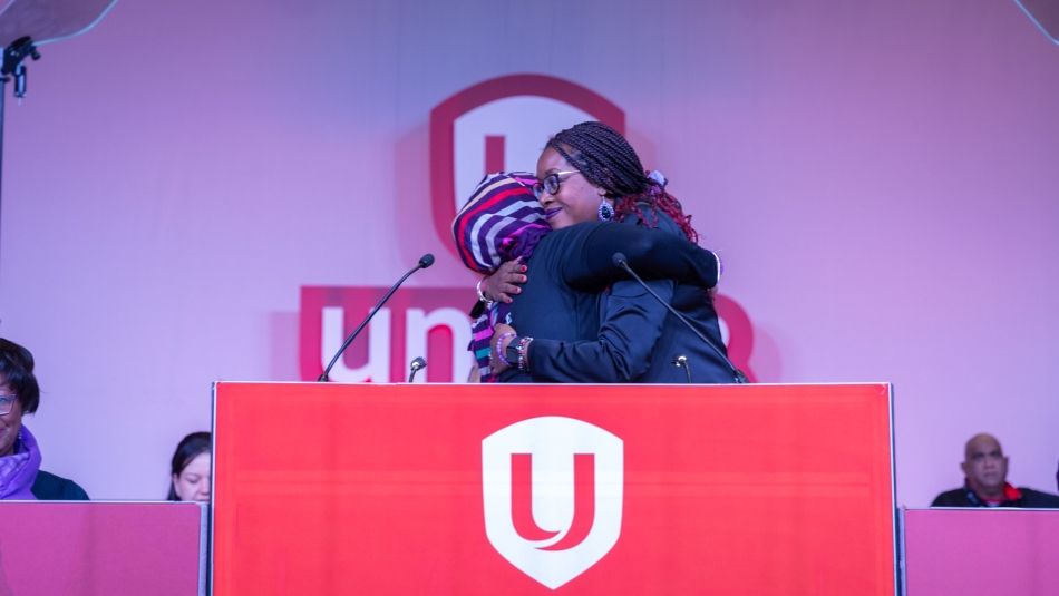 Two women at a Unifor poidum embrace 