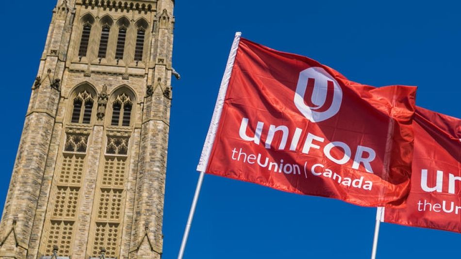 Two Unifor flags fly in front of the Peace Tower on Parliament Hill in Ottawa.