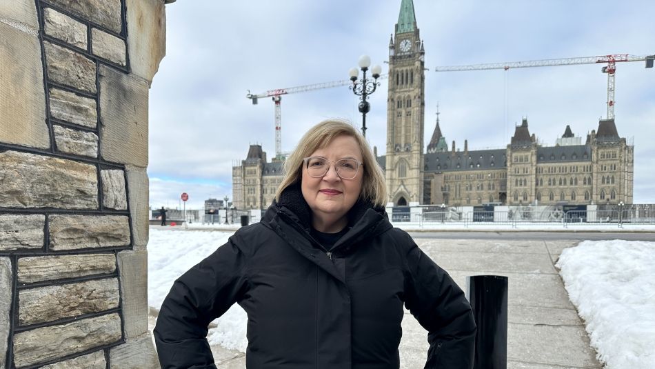 Lana Payne standing hands at hips in front of Parliament