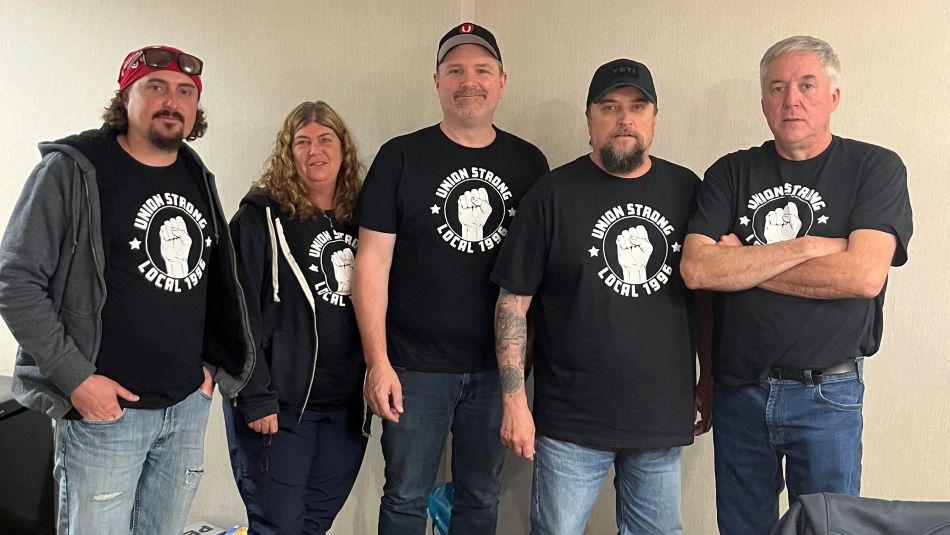 Five people standing wearing black t-shirts that read, Union Strong Local 1996