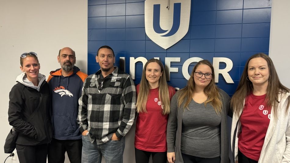 Six people standing in a room in front of a Unifor sign