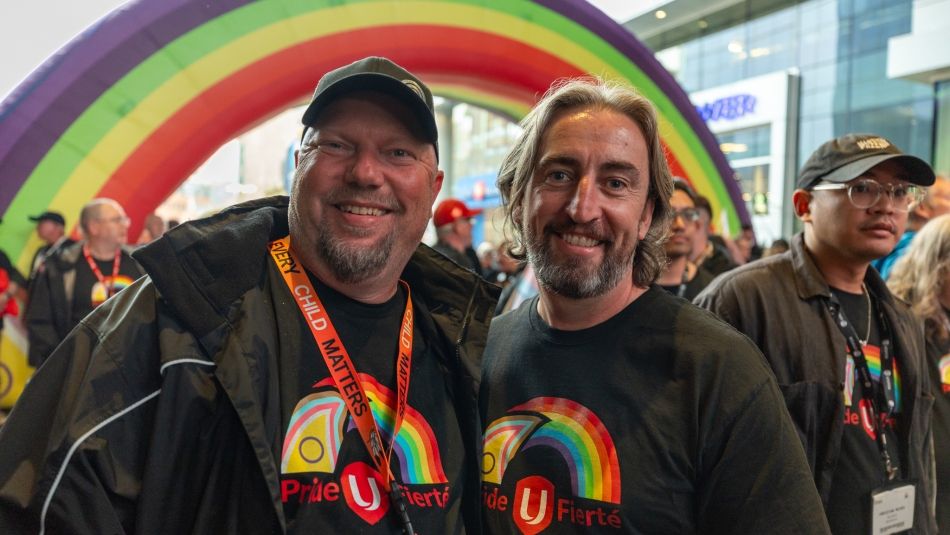 Two men under a balloon rainbow fixture.