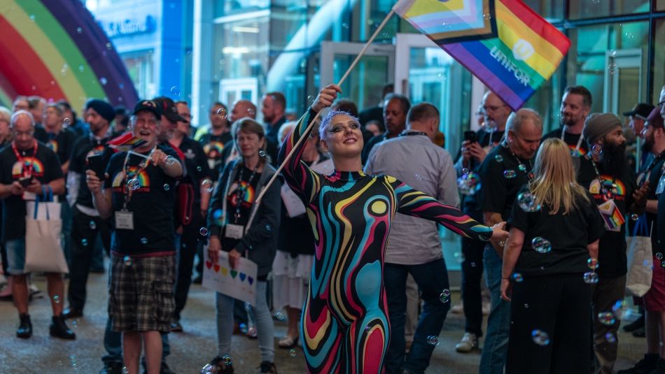 A performer holding a Unifor rainbow flag in a crowd.