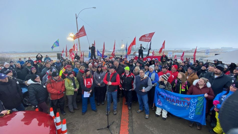 Scott Doherty, Adjoint exécutif au président parle au micro avec des dizaines de travailleuses et travailleurs derrière lui à Regina