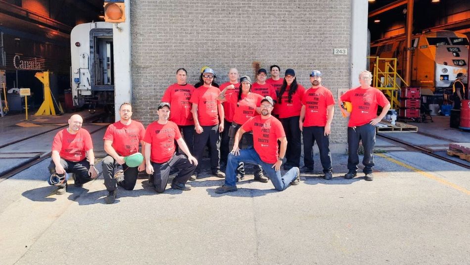 Via Rail workers wearing red t-shirts posing outside a terminal