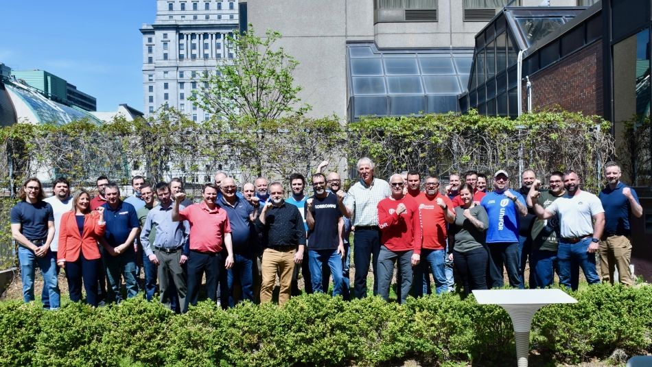 Renaud Gagné et des membres Unifor de Produits forestiers Résolu lèvent le poing en signe de solidarité et de victoire.