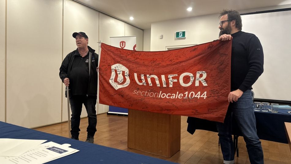 Two men holding a signed Unifor flag