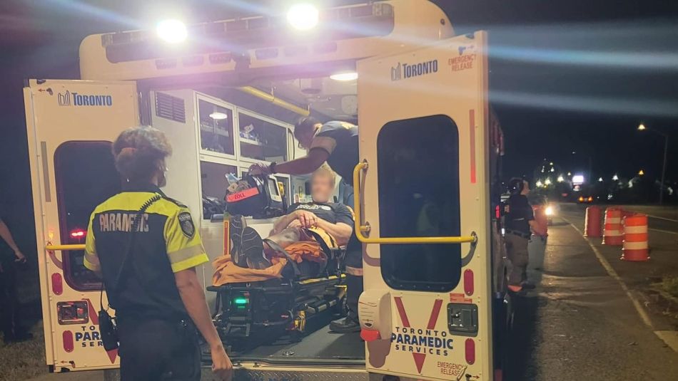 An injured Unifor member in the back of an ambulance at night with two paramedics attending to him. The member's face is digitally blurred.