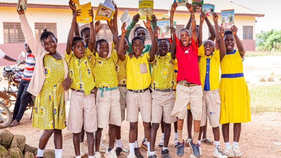 Un groupe d'enfants en uniforme tenant des livres au-dessus de leur tête.