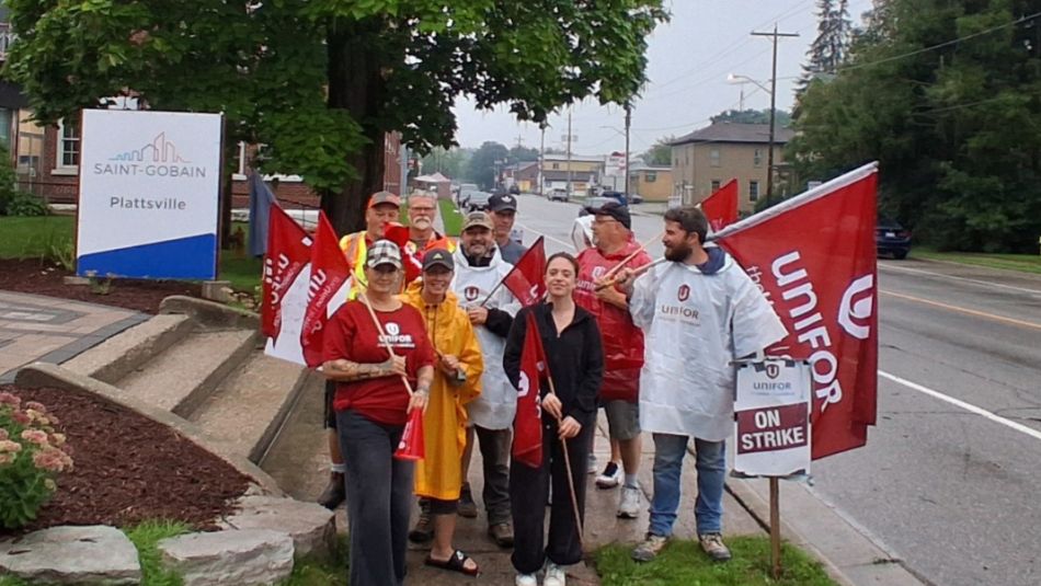 Picketers holding flags in front of the stairs at Saint-Gobain in Plattsville