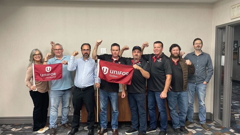 Un groupe de membres d'Unifor employés par la Corporation de gestion de la Voie maritime du Saint-Laurent levant le poing en signe de solidarité. 