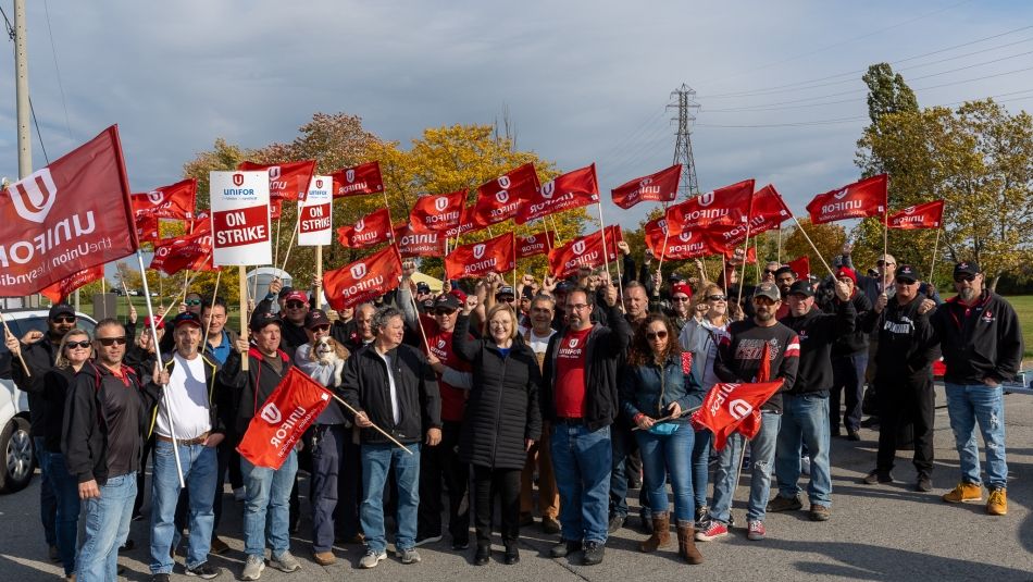 A large group of people holding up Unifor flags at the St. Lawrence Seaway picket line.