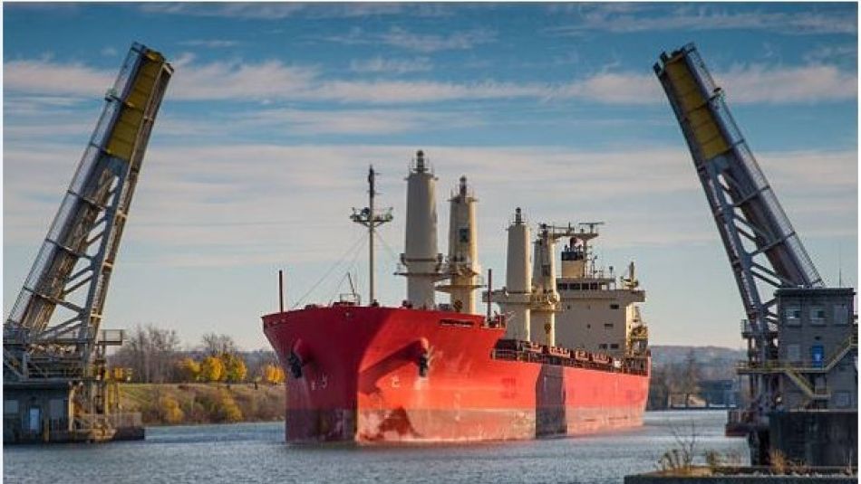 A large red ship passing through a lift bridge