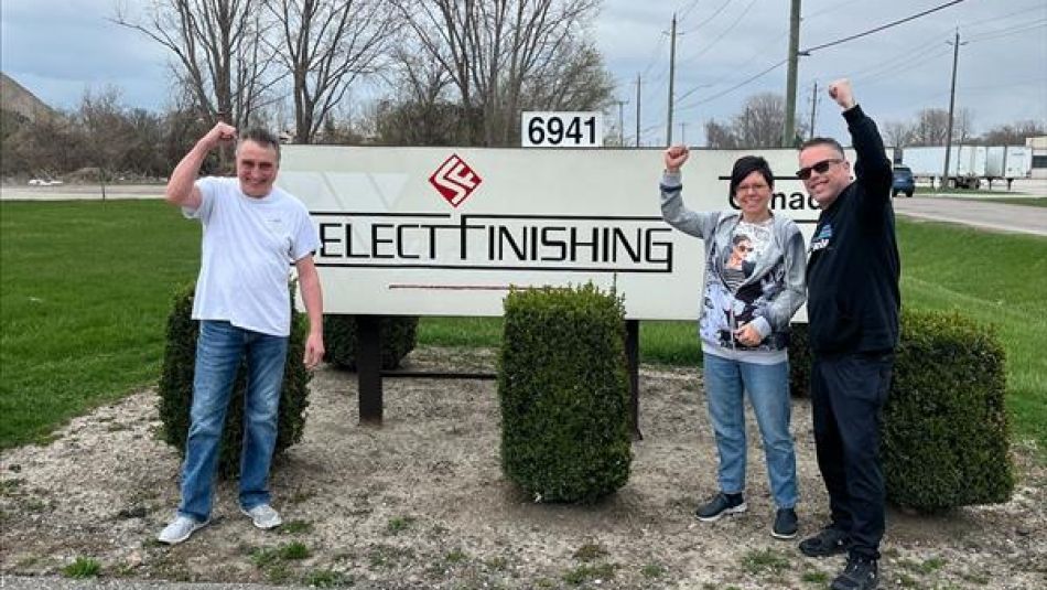 Three people standing outside beside a Select Finishing sign 