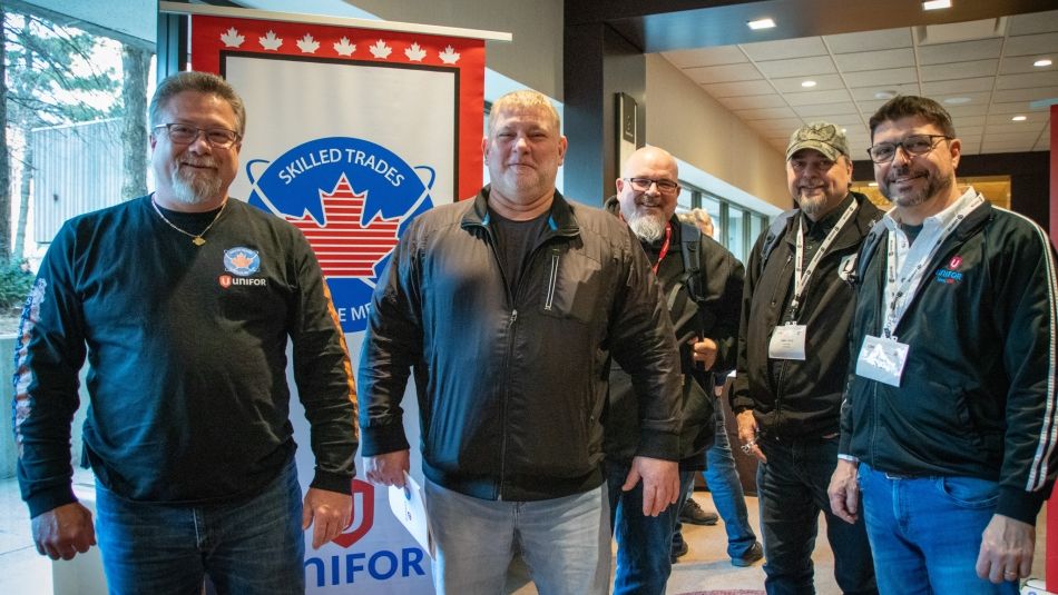 Five delegates at the Skilled Trades Conference standing in front of a pop up banner.