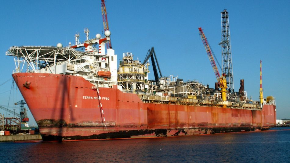 A red-hulled ship with an oil derrick.