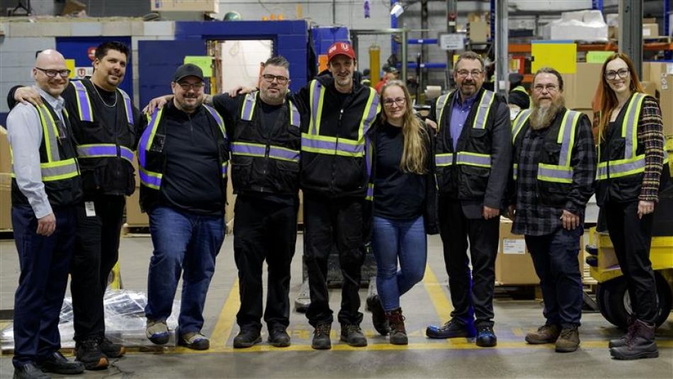 nine workers in dark safety uniforms proudly standing together smiling