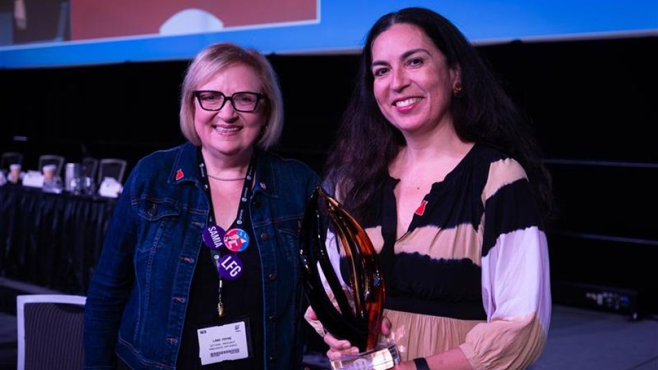 Two women holding a glass award