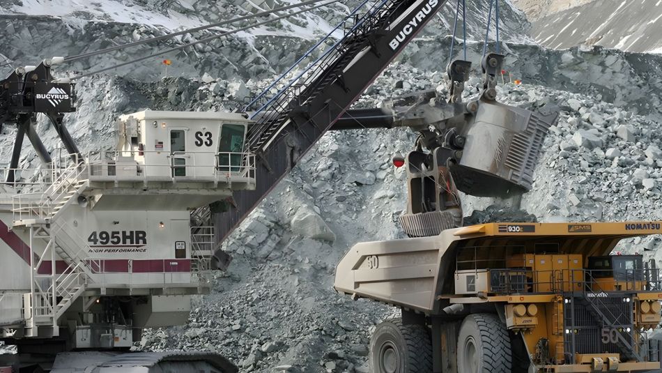 Une grande pelleteuse industrielle chargeant un camion de pierres.