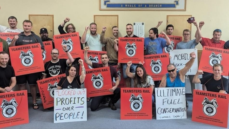 Teamsters members stand together holding signs and raising fists in solidarity.