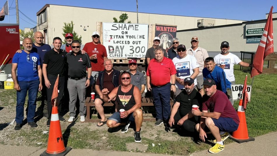 Titan Tool workers gathered outside of the plant around a sign that reads: Shame on Titan Tool locked out day 300.