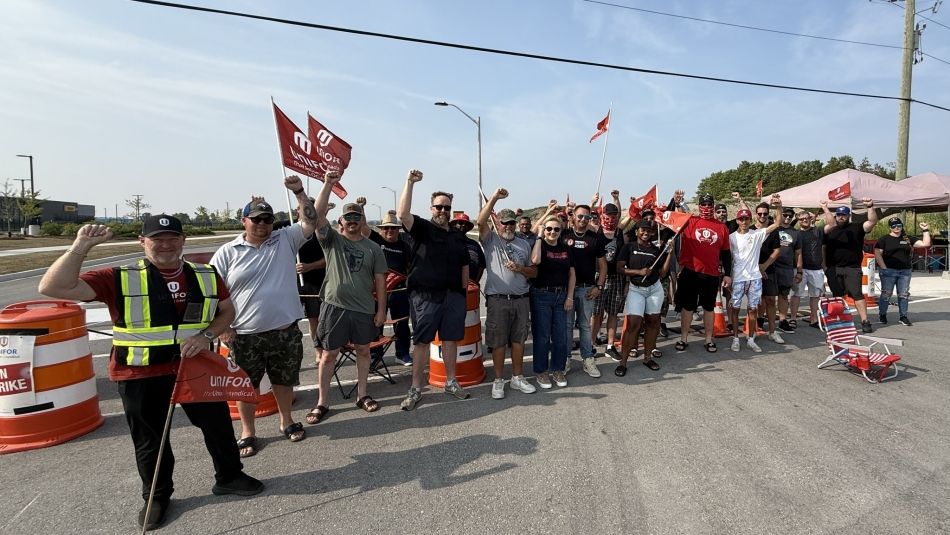 A large group holding flags on a labour picket line