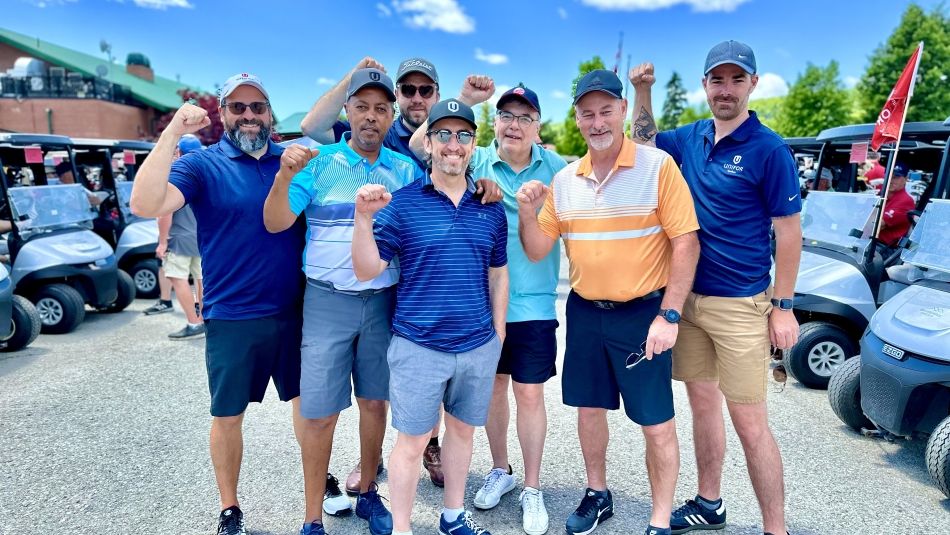 A group of men with their fists in the air with golf carts in the background.