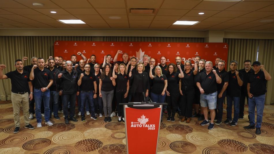 Large group of Ford bargaining committee members in black shirts posing with their fists in the air