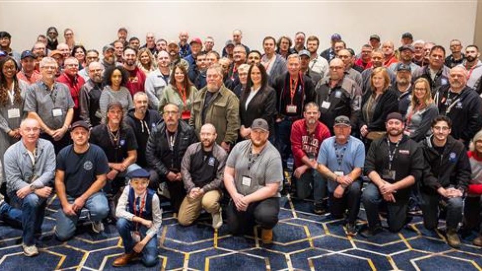 A large group posing in a hotel confernce room