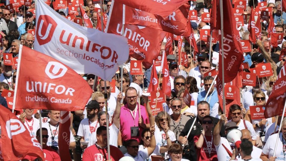 A crowd of people holding up Unifor flags