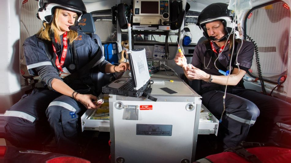 Two women pilots with helmets sitting inside an Ornge chopper.