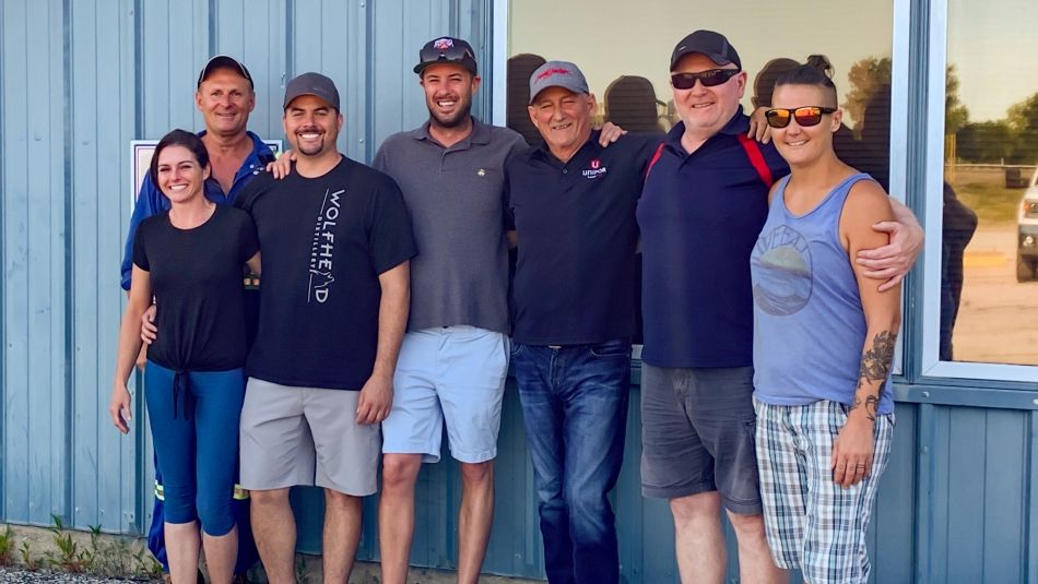 Seven members of the Local 200 bargaining committee posing for a photo outside of a blue building