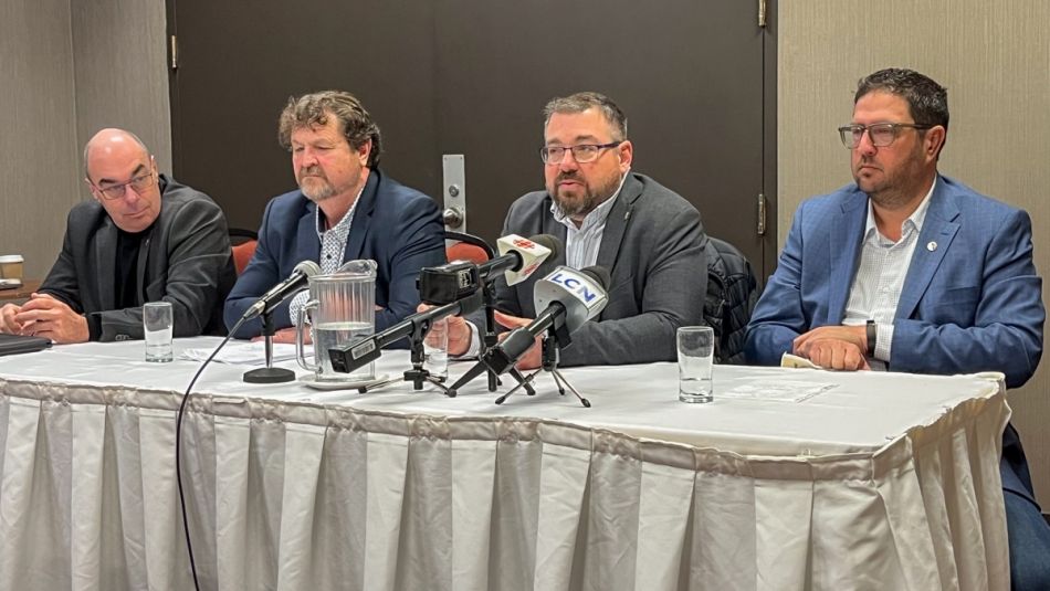 Four men seated at a table with microphones.