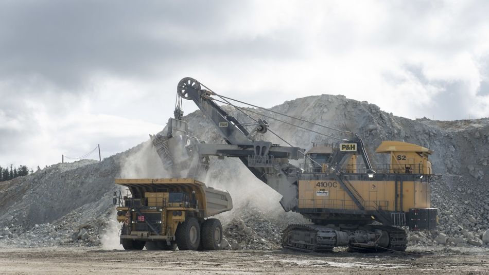 Deux véhicules miniers lourds devant une pile de minerai.