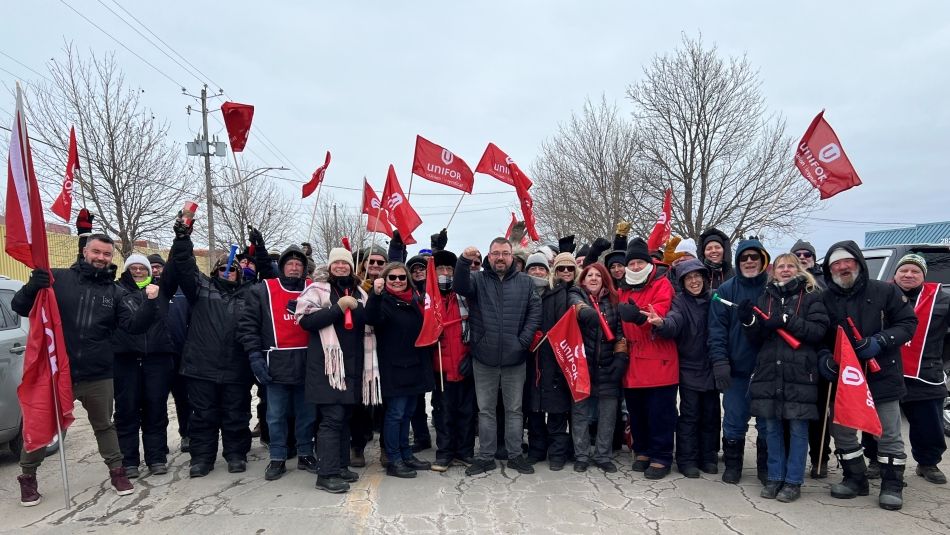 Daniel Cloutier posing with members on a picket line, many holding red flags.