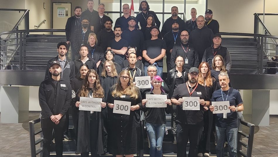 A group of people holding signs that read 300, days without a contract.