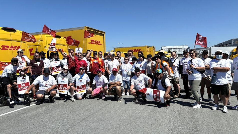 A group of people with strike signs and DHL vans in the background.