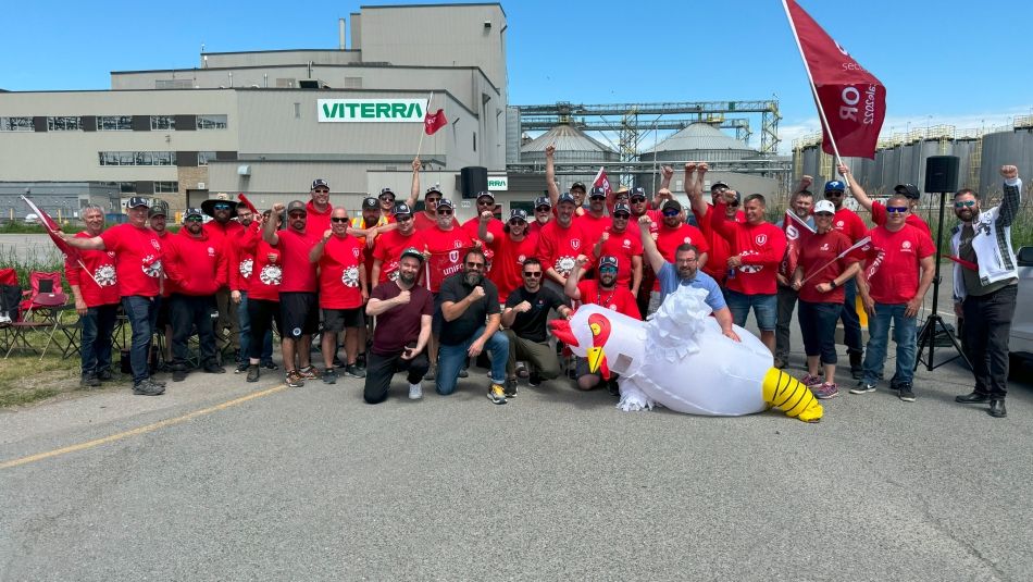 Un grand groupe posant avec des chemises rouges et une personne portant un costume de poulet géant gonflable.