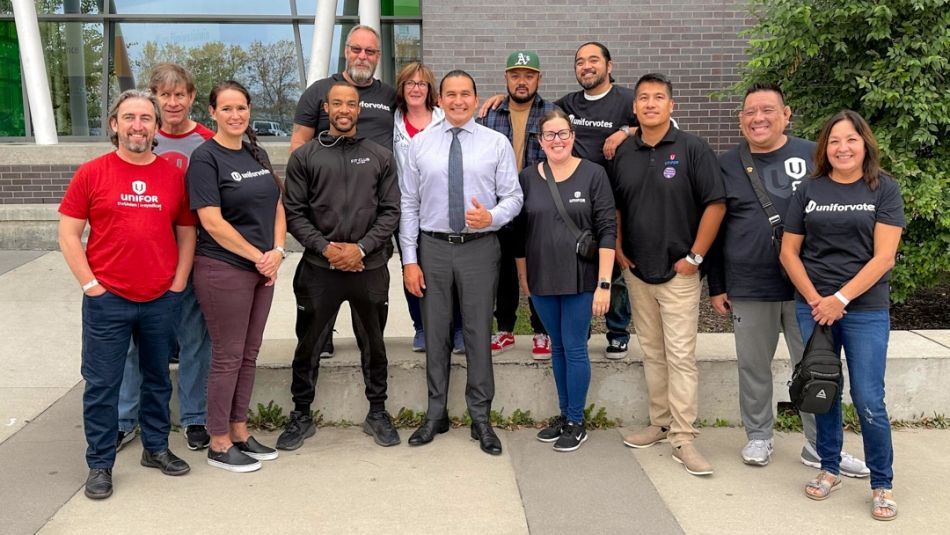 Twelve Unifor members standing outside with Manitoba Premier Wab Kinew