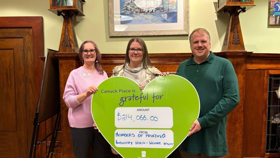 Three people holding an oversized green heart with donation amount.
