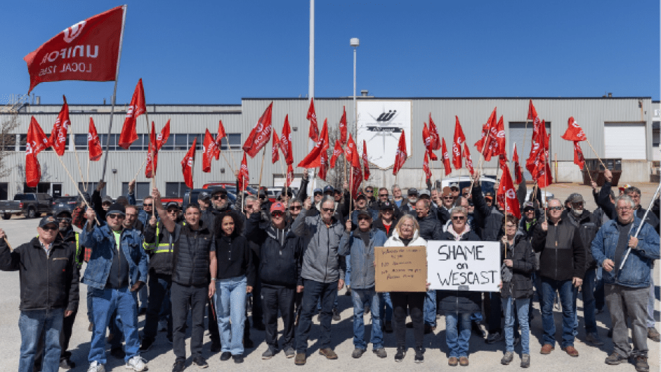 Wescast rally a large group holding up red Unifor flags and placcard reads, Shame on Wescast