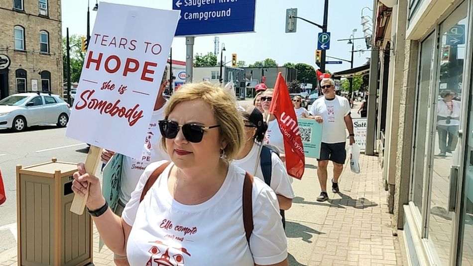Lana Payne walking outside with a placard that reads ‘She is somebody.'