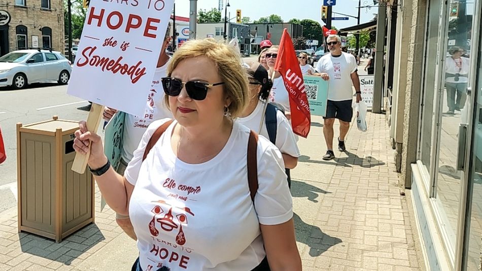 Lana Payne walking outside with a placard that reads ‘She is somebody.'