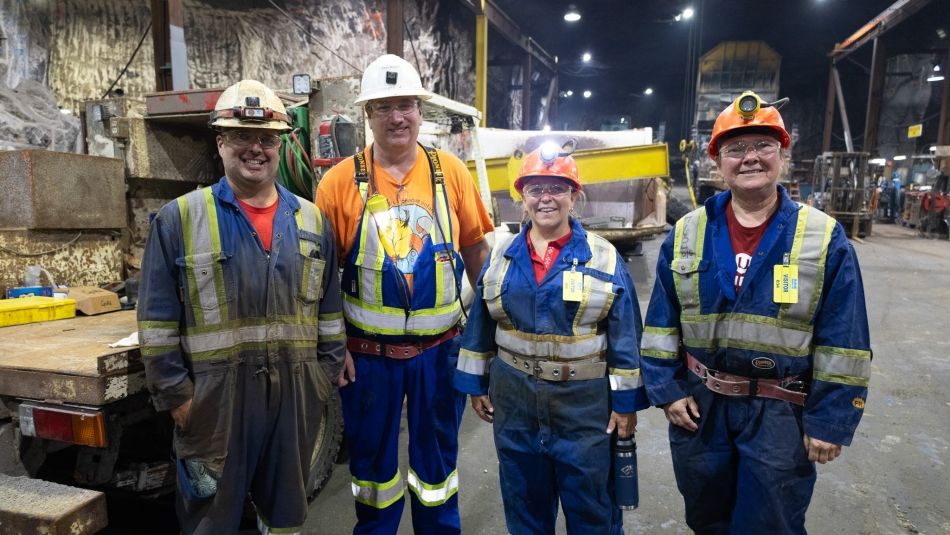 A small group of people wearing coveralls stand inside the Windsor Salt mine