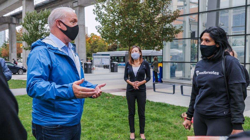 Premier Horgan speaks to Unifor members during the 2020 provincial election B.C. Premier John Horgan wearing a mask and speaking to a Unifor member outside of a Skytrain station in Vancouver