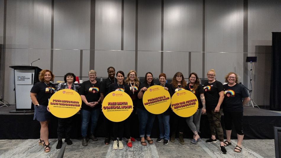 A group of women holding circular yellow signs.