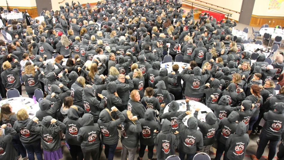 Women's group backs facing wearing their Unifor Rosie Solidarity sweatshirts fists in the air.