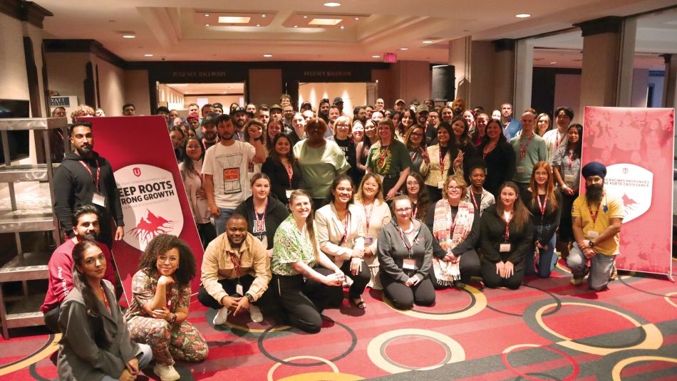 Un grand groupe pose à côté des bannières pop-up des jeunes travailleurs d'Unifor.