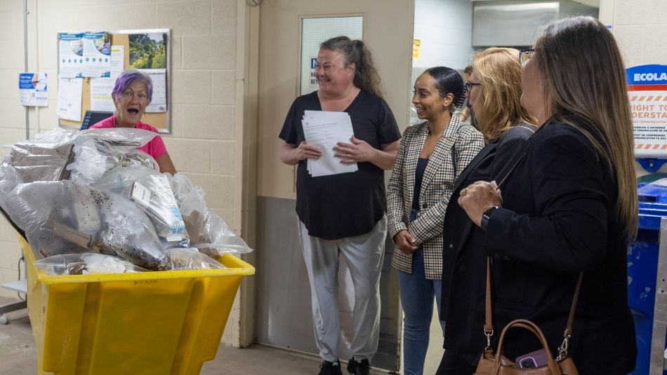 a women pusing a yellow garbage bin smiling with four women