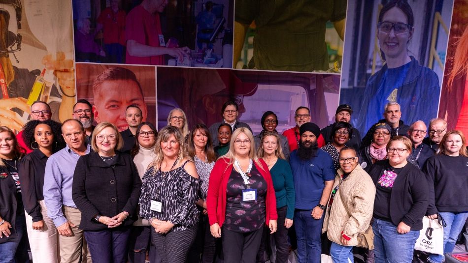 A group of people posing in front of a backdrop of worker profiles